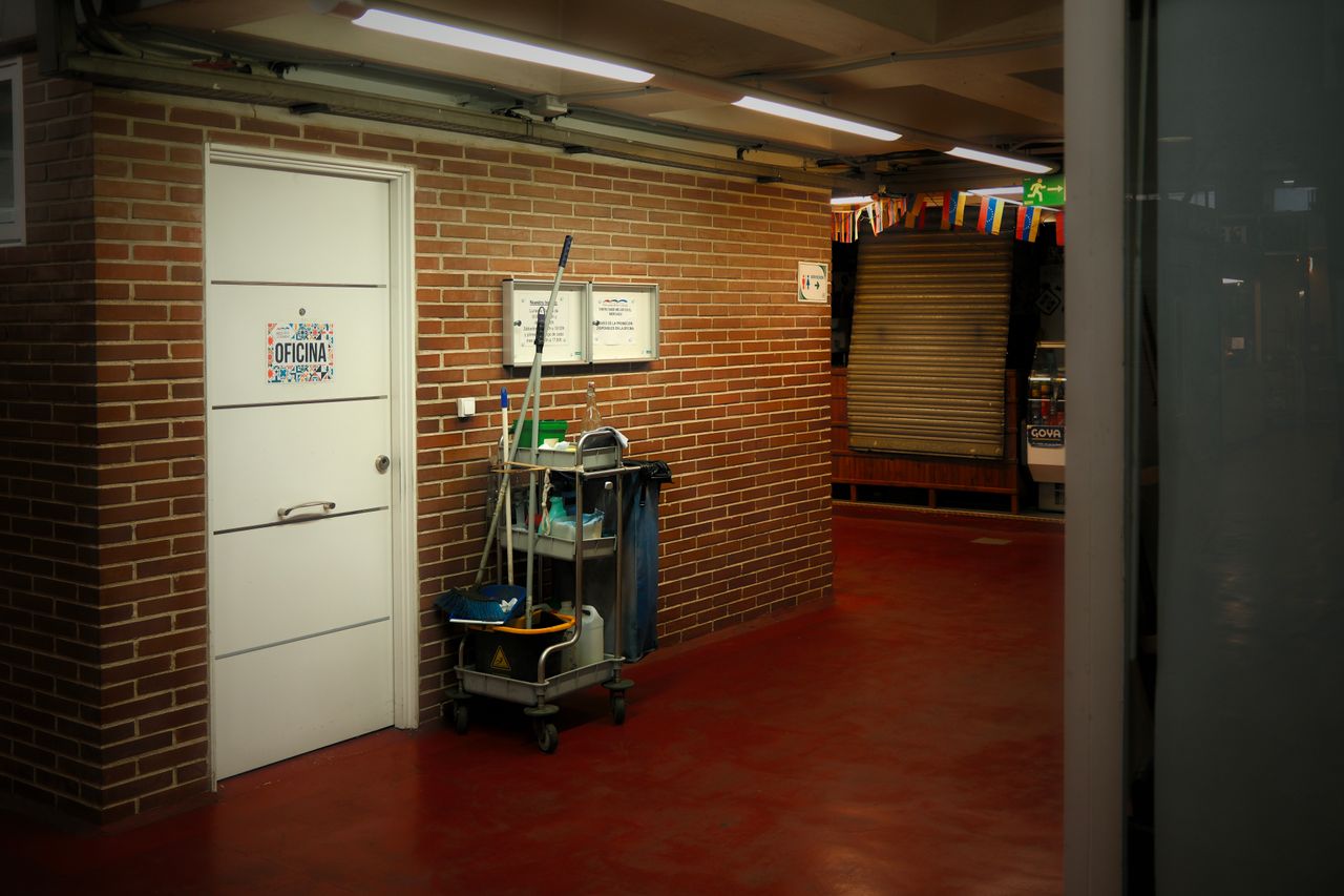 hero-img A brightly lit industrial hallway with a cleaning cart and supplies near an office door.